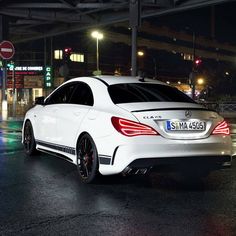 a white mercedes cla is parked on the street at night