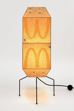 a cardboard box shaped like a mcdonald's sandwich on a black stand with a light bulb plugged in