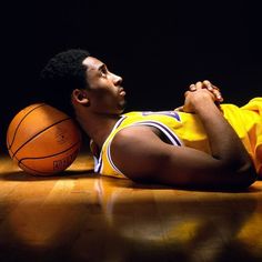 a man laying on the floor next to two basketballs