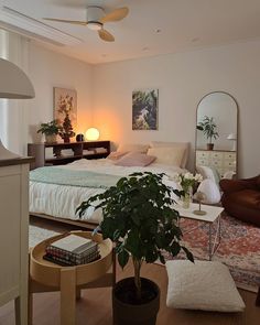 a bed room with a neatly made bed next to a chair and table in front of a mirror