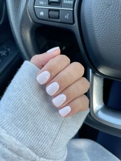 a woman's hand holding onto the steering wheel of a car with white nails