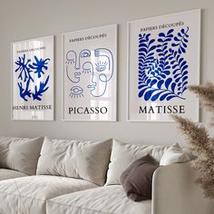 three blue and white art prints hang on the wall above a couch in a living room