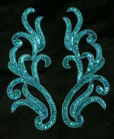 two blue sequins are on a black background with white and green designs in the middle