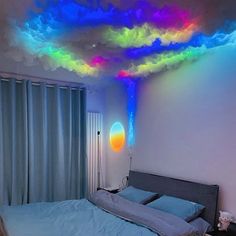 a bed room with a large bed and a rainbow colored light on the ceiling above it