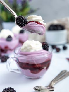 a spoon full of berries and cream on top of a table with other desserts