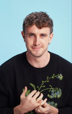 a man in a black shirt is holding his hands together and looking at the camera