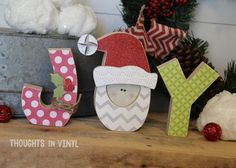 wooden letters decorated with santa claus and snowman hats sit on a shelf in front of christmas decorations