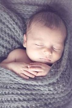 a newborn baby wrapped in a gray blanket