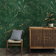 a green wallpaper with gold leaves on it and a wooden cabinet in the foreground