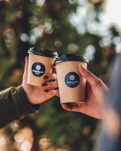 two people holding coffee cups in their hands