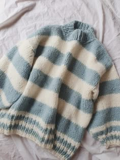 a blue and white sweater laying on top of a bed