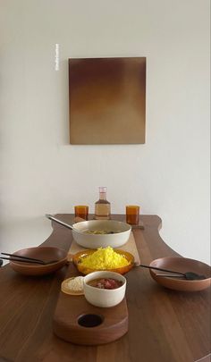 a wooden table topped with bowls filled with food