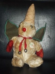 a stuffed animal with a red nose and green wings on it's head sitting on a black surface