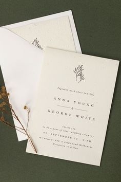 two wedding cards on top of each other next to some dried flowers and paper envelopes