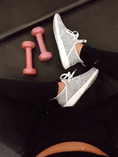 a person's feet with white sneakers and pink dumbs