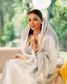 a woman sitting on a couch wearing a veil and holding a cross in her hand