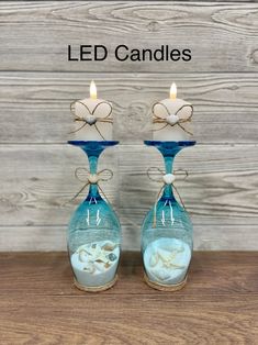 two blue glass candle holders with seashells in them and the words led candles