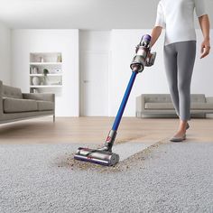 a woman is using a vacuum to clean the floor in her living room with carpet