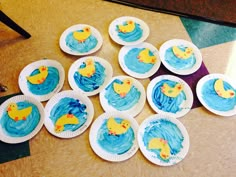 paper plates with blue frosting and yellow rubber ducks on them sitting on a table