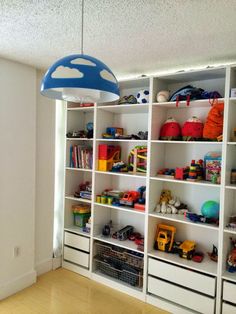 a room filled with lots of white shelves and toy bins on top of them