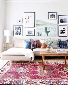 a living room filled with lots of pictures on the wall above a couch and coffee table