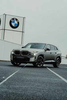 a silver car parked in front of a bmw dealership with the logo on it