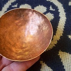 a hand holding a metal bowl on top of a rug