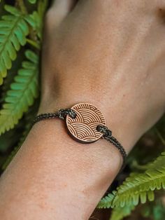 a woman's hand wearing a bracelet with an engraved disc on it