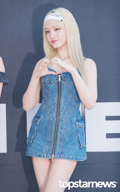 a young woman wearing a denim dress and headband poses in front of a wall