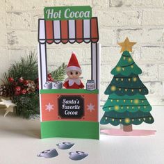 a christmas card with a santa's favorite cocoa machine in front of a tree