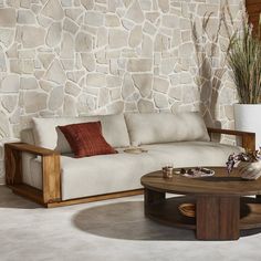 a white couch sitting next to a wooden table on top of a stone covered floor