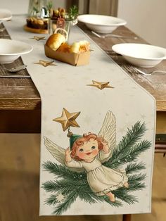 a christmas table runner with an angel holding a star on it and pine branches in the foreground