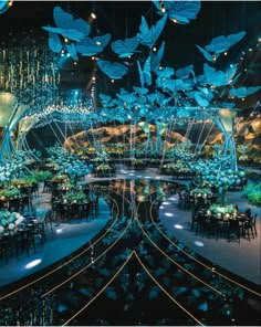 a large room filled with lots of tables covered in blue flowers and hanging chandeliers