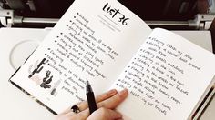 a person holding a pen and writing on an open book in front of a typewriter