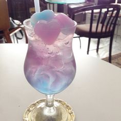 a purple and blue drink sitting on top of a table next to a lit candle