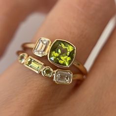 a woman's hand with three different colored rings on her fingers and one has a yellow diamond