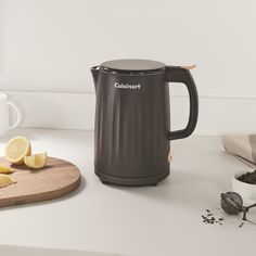 a coffee pot sitting on top of a counter next to sliced lemons