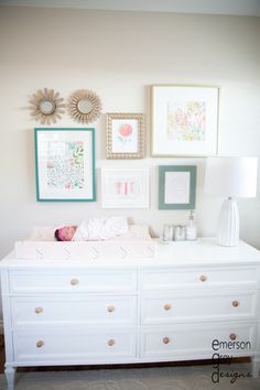 a baby's crib is shown with pictures on the wall and framed art above it