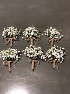 six bouquets of white flowers tied with twine and burlap on a metal surface