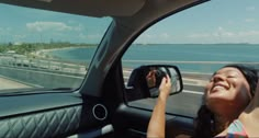 a woman sitting in the passenger seat of a car with her head out the window