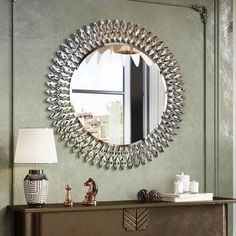 a mirror is hanging on the wall above a console table with a lamp and vase