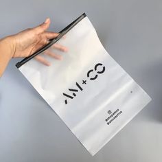 a person's hand holding a white paper bag with the word m & s printed on it