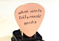 a pink guitar pick that says when words fail music speaks