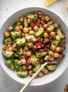 a white bowl filled with cucumber and chickpeas