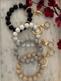 four different bracelets on a marble surface with red flowers in the backgroud