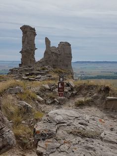 an old rock formation on the side of a hill with rocks and grass around it