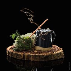 a black mug with a stick sticking out of it sitting on top of a tree stump