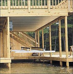 a wooden dock with a hot tub and stairs leading up to the deck area above it