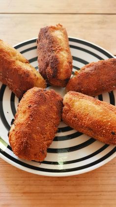 four fried food items on a black and white striped plate with wood table in the background