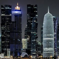 the city skyline is lit up at night with skyscrapers and other buildings in the foreground